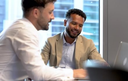 business men meeting and talking in the office. there is a laptop on the table.