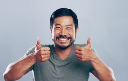 4k video footage of a young man showing thumbs up against a grey background